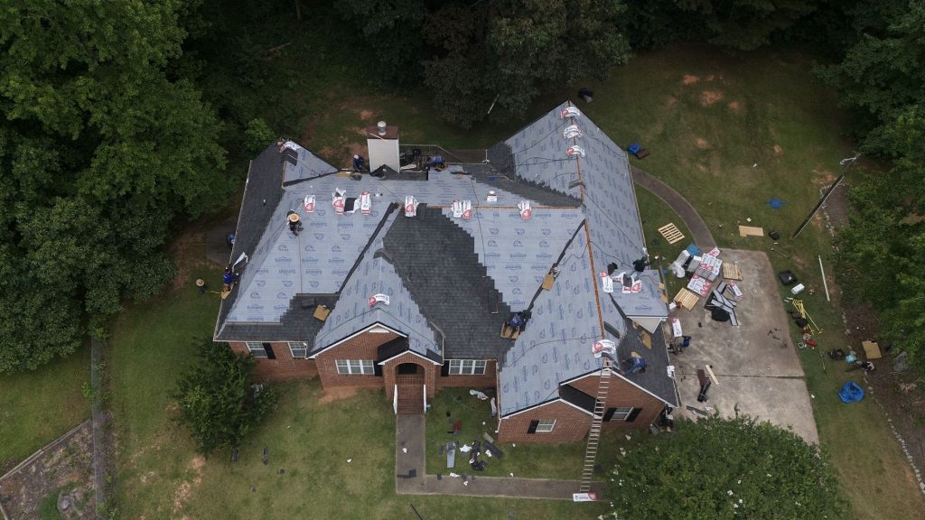 Roofers on a house with during a roof replacement