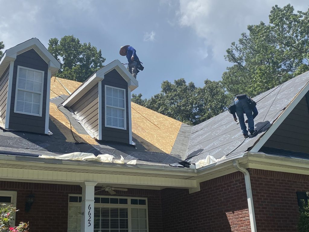 Roofers on a house with during a roof replacement