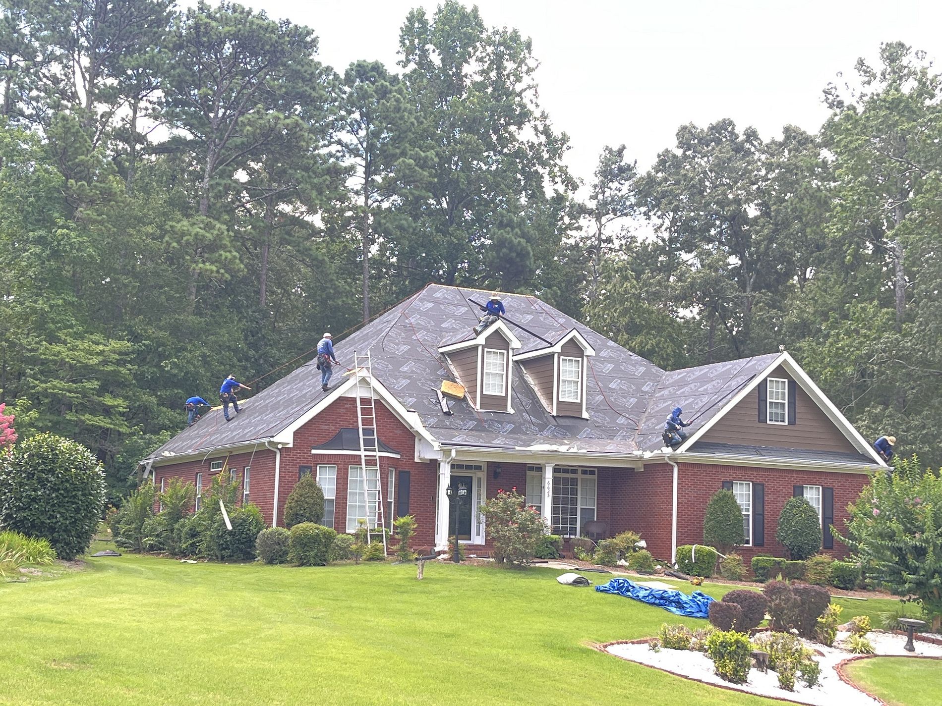 Roofers on a house with during a roof replacement
