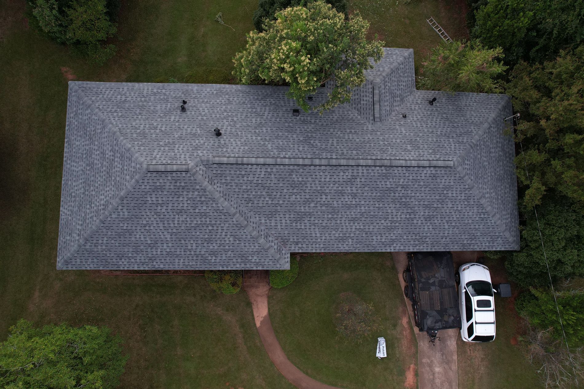 Top down image of a new gray asphalt shingled roof replacement on a house.