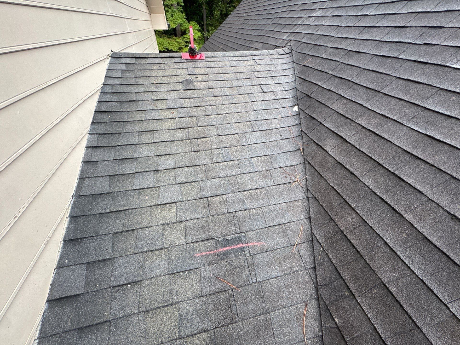 Photo from a roofer on a roof showing a shingle that has been torn off due to wind damage.