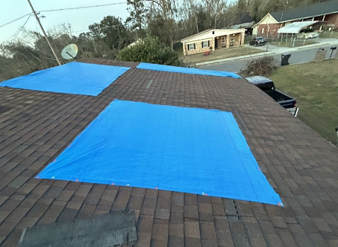 Image of a roof with multiple blue tarps needing roof repairs